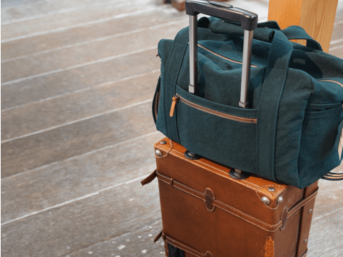 写真:茶色いスーツケースの上に緑のバックが乗っている